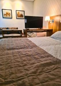 a hotel room with a bed and a flat screen tv at MG Apto com cozinha in Cuiabá +12 photos