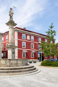 uma estátua em frente a um edifício vermelho em AP Dona Aninhas em Viana do Castelo