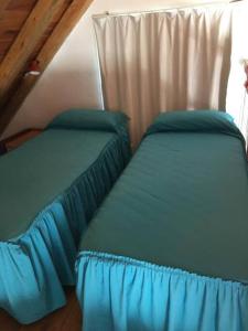 サン・ラファエルにあるCasa en Los Reyunos, Ubicación perfecta Frente al lagoの屋根裏のベッドルームに青いシーツが備わるベッド2台