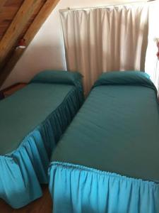 two beds with blue sheets in a attic bedroom at Casa en Los Reyunos, Ubicación perfecta Frente al lago in San Rafael