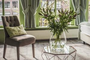 ein Wohnzimmer mit einem Stuhl und einer Vase mit einer Pflanze in der Unterkunft 't Hotel in Amsterdam