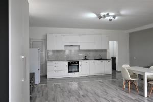 a kitchen with white cabinets and a table with chairs at Bright and cozy apartment nr. 1 in Chişinău