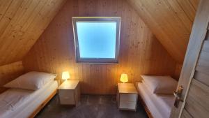 2 łóżka w drewnianym pokoju z oknem w obiekcie Domki na Żytniej w mieście Kopalino