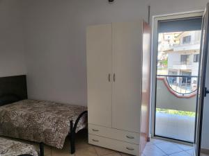 ein Schlafzimmer mit einem weißen Schrank, einem Bett und einem Fenster in der Unterkunft San Silvestro House in Cariati
