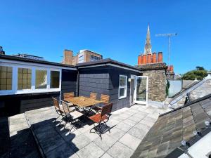 a patio with a wooden table and chairs on a roof at Cityscape Haven: 1 Bedroom Apartment with Terrace and City view in Bournemouth