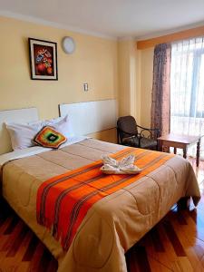 Una habitación de hotel con una cama grande con una bata. en SUMAQ PUNO, en Puno