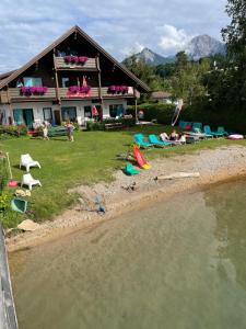 una casa con persone sedute sulla riva di una spiaggia di Haus Kleinbichler a Faak am See