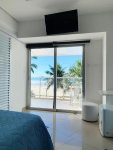 a bedroom with a view of the beach with a television at Asturias Mall & Suítes in Guarujá
