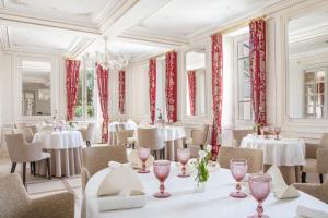 コニャックにあるLa Nauve, Hôtel & Jardin - Relais & Châteauxの白いテーブルと椅子、赤いカーテンが備わるレストラン