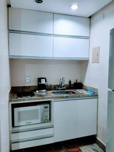 a kitchen with white cabinets and a microwave at Flat LakeSide -Vista para o lago C17 in Brasilia