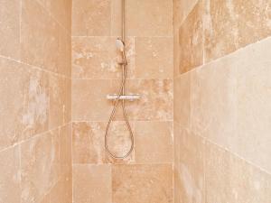 a shower with a hose in a tiled bathroom at La bambouseraie de sulauze in Miramas