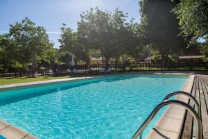 une grande piscine avec un banc et des arbres dans l'établissement Camping La Ferme de Perdigat, à Limeuil