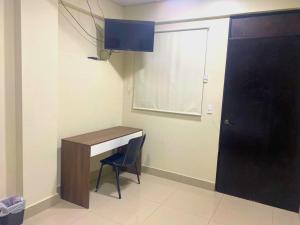 a room with a desk with a chair and a door at Hotel La Capilla - Suites & Apartments San Benito in San Salvador