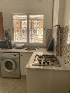 y cocina con fogones y lavadora. en La Marsa Maison avec jardin, terrasse parking Wifi Illimité en La Marsa