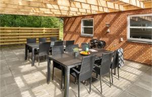 um pátio com mesas e cadeiras pretas e uma parede de tijolos em Gorgeous Home In Grindsted With Kitchen em Grindsted