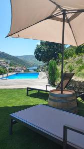 uma mesa de piquenique com um guarda-sol ao lado de uma piscina em Dois Lagares House no Pinhão