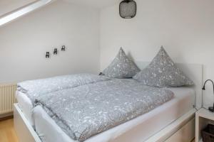 Dormitorio blanco con cama con almohadas grises en Weitblick, en Breitnau
