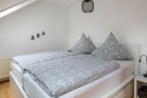 a white bedroom with a bed with gray pillows at Weitblick in Breitnau