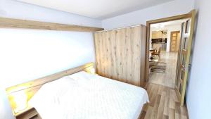 a bedroom with a white bed and a wooden wall at Kros Properties - Central in Varna City