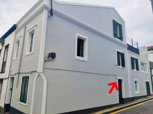 a white building with a red arrow on it at Santi e Benny Apartment in Ponta Delgada