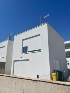 a white building with two windows on top of a wall at Apartman Karmen in Brodarica