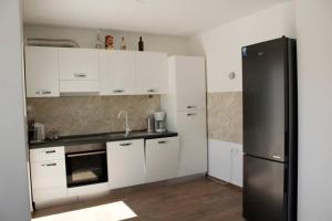 kuchnia z białymi szafkami i czarną lodówką w obiekcie Apartman Karmen w mieście Brodarica