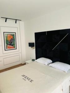 een bed met een zwart hoofdeinde in een kamer bij Hotel AVENUE in Ravda