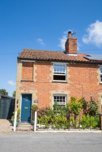 a red brick house with a blue door at Hall Cottage Bramfield Suffolk in Bramfield