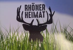 un panneau de cerf dans l'herbe avec les mots honor himant dans l'établissement Historischer Hof, einladend für Mensch und Tier., à Schenklengsfeld