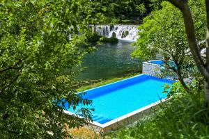 a swimming pool next to a waterfall and a river at Konoba Slapovi in Jajce