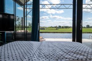 a room with a bed with a view of a lake at 4 to 6 persons waterfront villa in Roelofarendsveen
