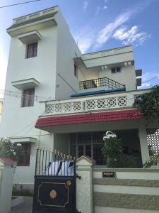 Un grand bâtiment blanc avec un balcon est disponible. dans l'établissement A Sweet home Homestay Second Floor, à Palni