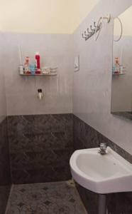 La salle de bains est pourvue d'un lavabo et d'un miroir. dans l'établissement A Sweet home Homestay Second Floor, à Palni