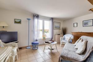 a living room with a couch and a tv at Paisible escale à Talmont-Saint-Hilaire avec piscine in Saint-Jean-dʼOrbetiers