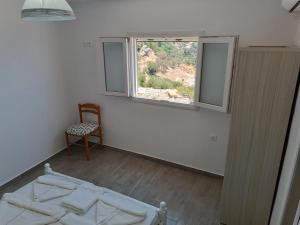 ein Schlafzimmer mit einem Bett, einem Fenster und einem Stuhl in der Unterkunft Silver View Aprovato in Apróvaton