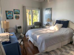 a bedroom with a bed and a chair and a window at Algonquin Island 'Luxe' Cottage at the edge of the Park in South River