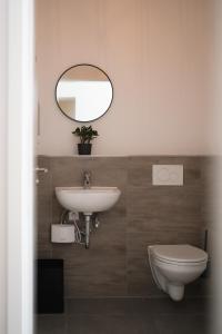 ein Badezimmer mit einem Waschbecken, einem WC und einem Spiegel in der Unterkunft Ein, Zwei- oder Mehrbettzimmer/ Monteurszimmer in Leipzig