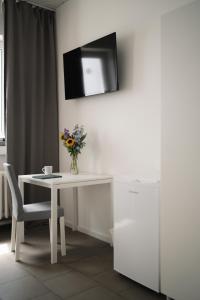 einen weißen Tisch mit einer Blumenvase und einem TV an der Wand in der Unterkunft Ein, Zwei- oder Mehrbettzimmer/ Monteurszimmer in Leipzig
