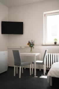 una sala da pranzo bianca con tavolo e due sedie di Ein, Zwei- oder Mehrbettzimmer/ Monteurszimmer a Lipsia