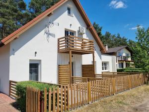 une maison blanche avec une clôture en bois dans l'établissement Ostoja, à Ostrowo
