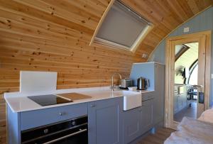a kitchen with a white counter top and wooden walls at Macree Pod in Taynuilt