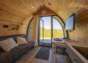 a room with a couch and a desk in a tiny house at Macree Pod in Taynuilt