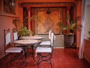 einen Tisch und Stühle in einem Zimmer mit orangefarbenen Wänden in der Unterkunft Riad Malida Marrakech in Marrakesch