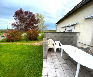 a patio with two white chairs and a bench at Maison avec terrasse - 12 personnes in Saint-Yan
