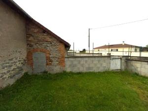 un bâtiment en briques avec une cour en herbe à côté d'un mur dans l'établissement Maison avec terrasse - 12 personnes, à Saint-Yan