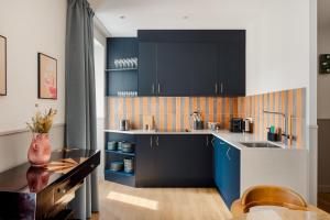 a kitchen with blue cabinets and a sink at Edgar Suites Montmartre - Paul Albert in Paris