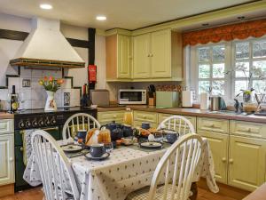 een keuken met een tafel en stoelen met eten erop bij The Old Thatch in Hailsham