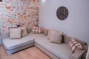 a couch with pillows and a clock on a wall at Ktima Faki in Litochoro