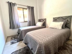 1 dormitorio con 2 camas y ventana en ASAMA appartement avec piscine en Marrakech
