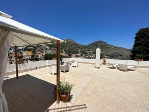 un patio con dosel blanco, mesas y sillas en MIRA taormina rooms en Taormina